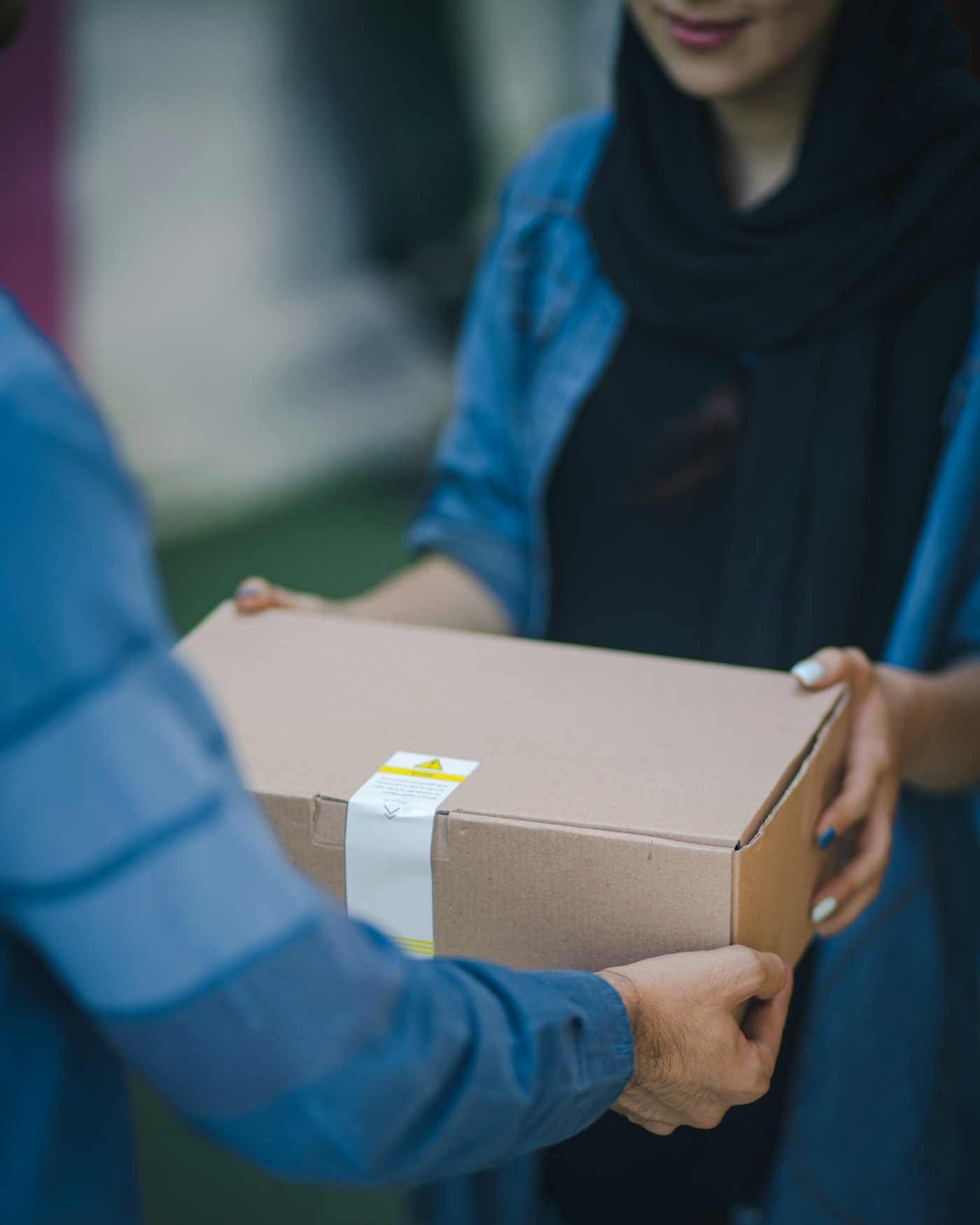 A person handing over a parcel wrapped in brown paper